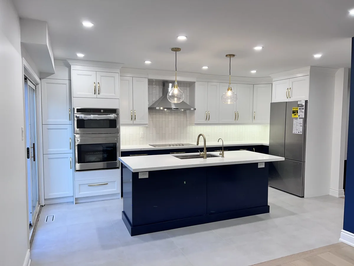 Navy blue kitchen island with brass cabinet pulls and pendant lights in a GTA kitchen renovation