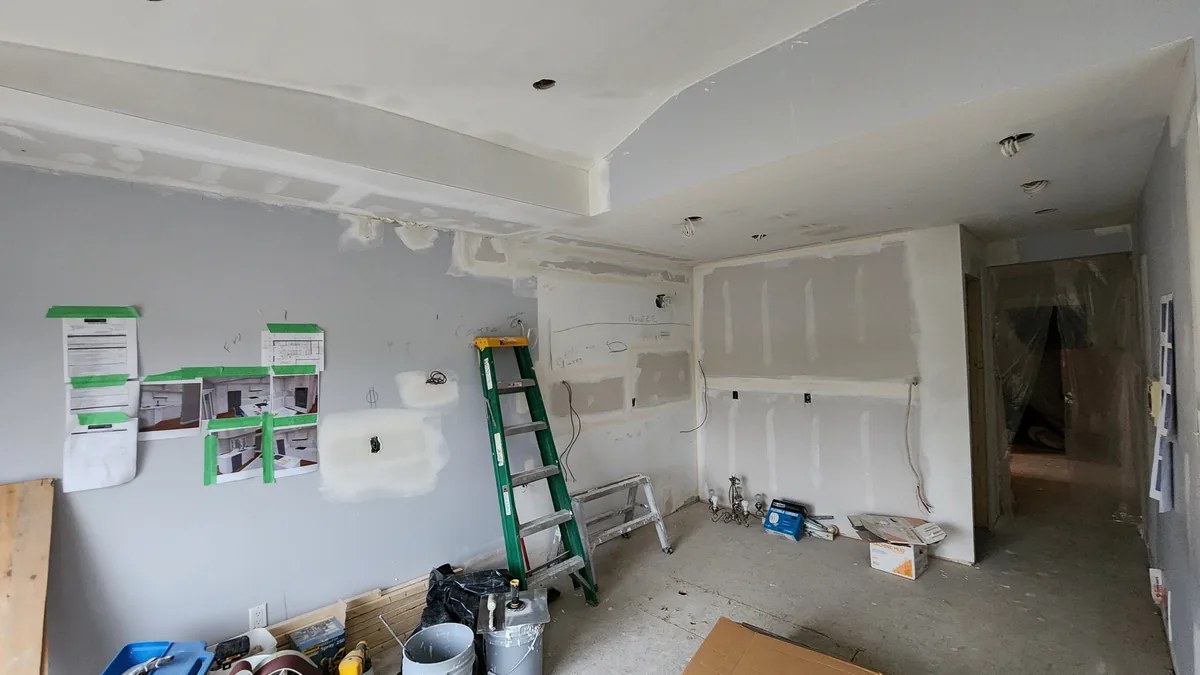 Kitchen mid-renovation with layout drawings taped to drywall
